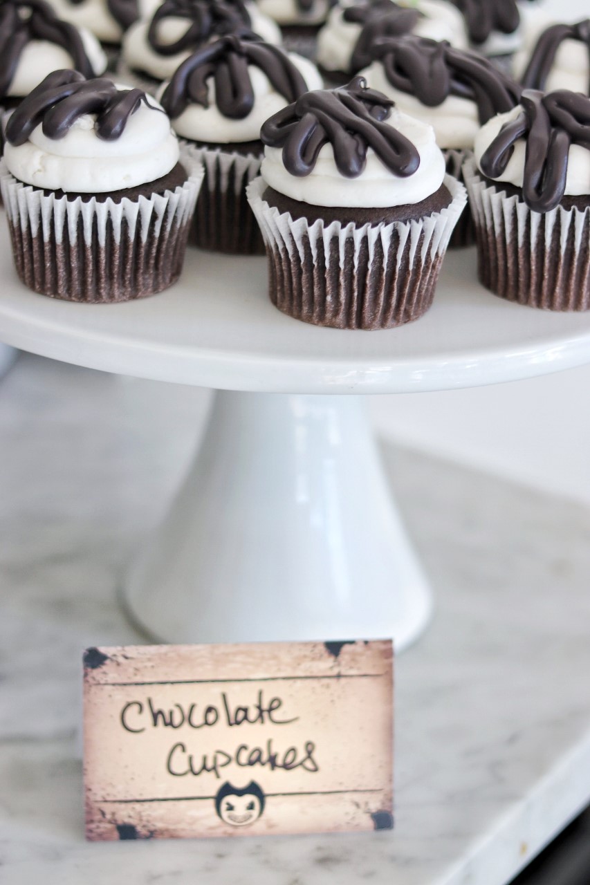 dessert idea for a bendy and the ink machine birthday party: chocolate cupcakes with white frosting and black candy melt drips