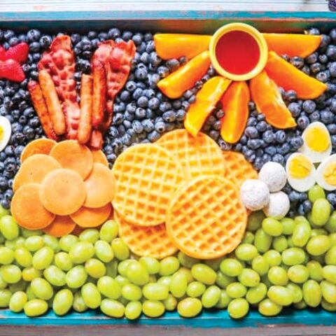 Tray of waffles, grapes, berries and more kid friendly foods.