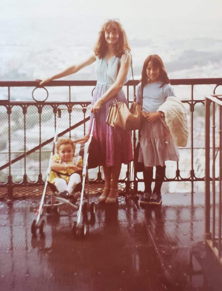Paris with kids - throwback photo of me (in the stroller) with my mom and sister on the second floor of the Eiffel Tower in Paris in 1982