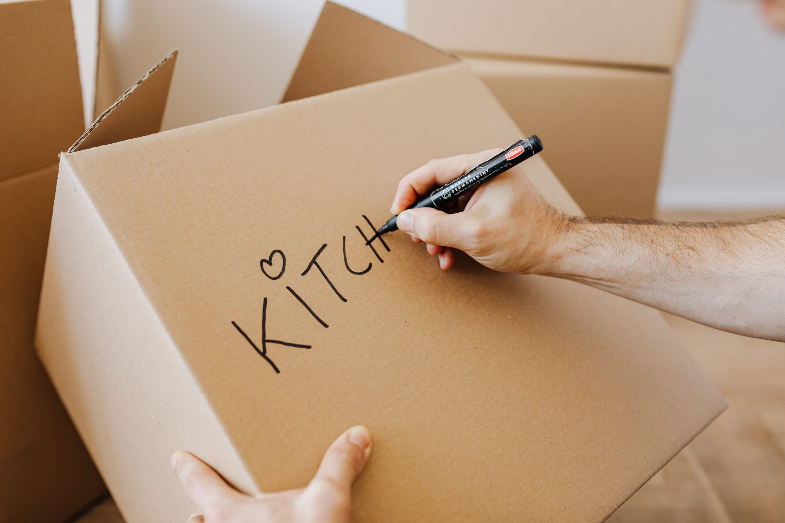 Person labeling cardboard boxes while preparing to move