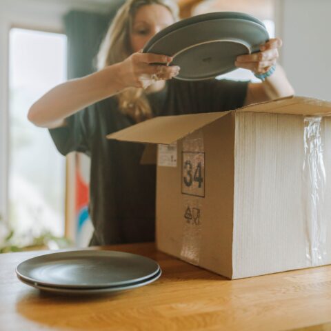Person holding green plates while packing her kitchen.