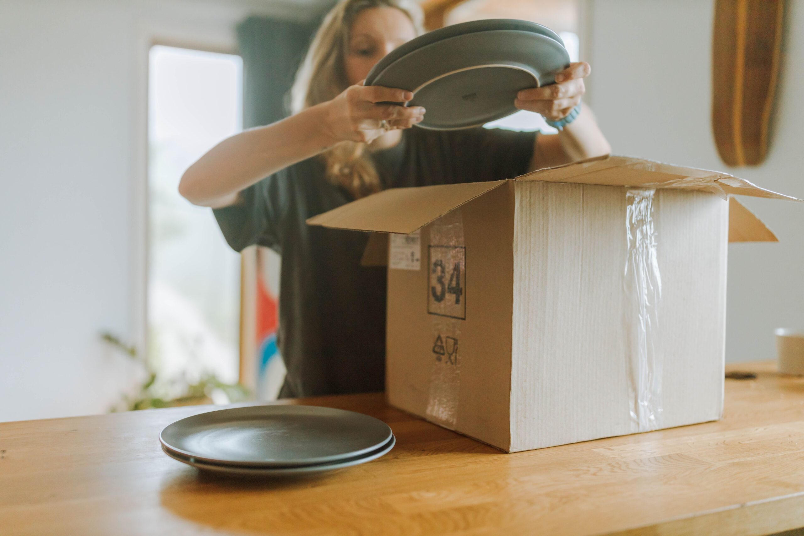 Person holding green plates while packing her kitchen.